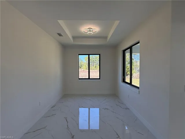 Empty room with light marble finish flooring and a raised ceiling