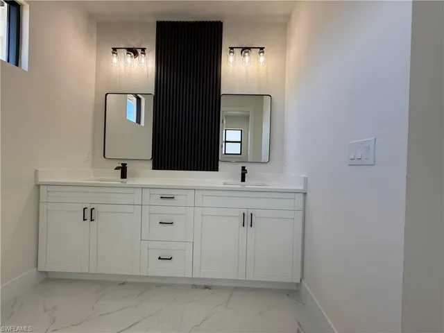 Bathroom featuring double vanity and light marble finish floors