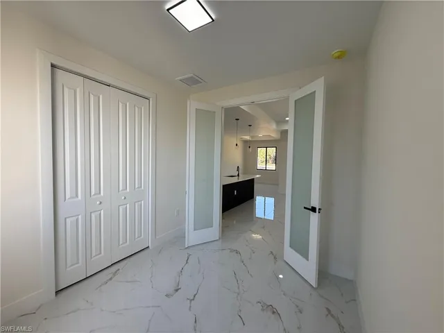 Unfurnished bedroom with light marble finish flooring and a closet