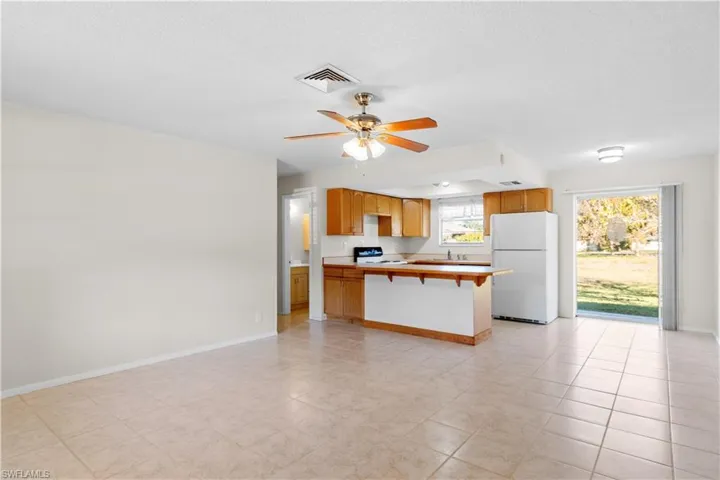 Kitchen with a breakfast bar, range, kitchen peninsula, white fridge, and ceiling fan