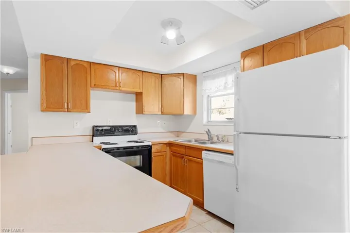 Kitchen Oak cabinets, white appliances, and raised ceiling
