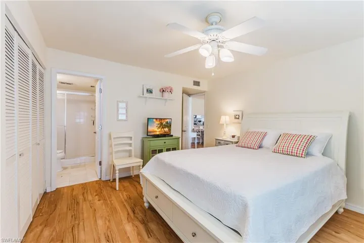 Bedroom with light wood-style floors, a ceiling fan, a closet, and ensuite bath