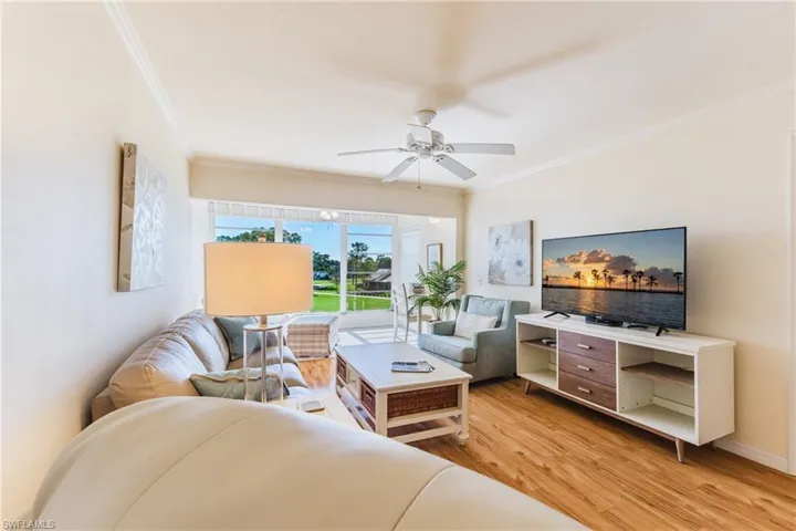 Living area featuring light wood-style floors, ceiling fan, and ornamental molding