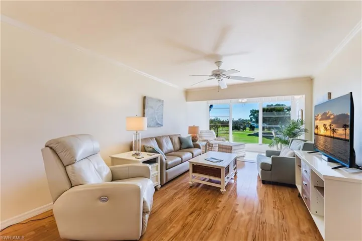 Living area featuring light wood-type flooring, ornamental molding, and ceiling fan
