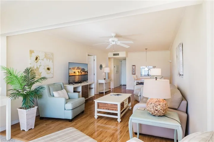 Living room featuring ceiling fan, ornamental molding, and light wood-style flooring
