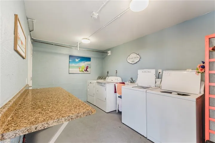 Shared laundry with concrete block wall, concrete flooring, and separate washer and dryer