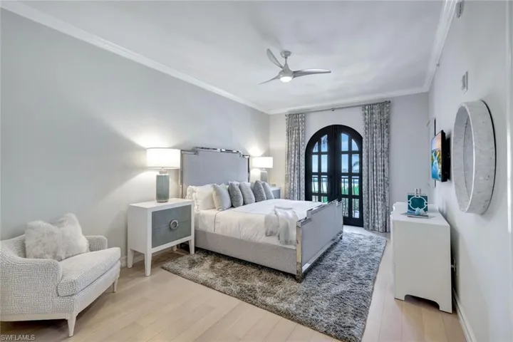 Bedroom featuring ceiling fan, light hardwood / wood-style floors, crown molding, and french doors