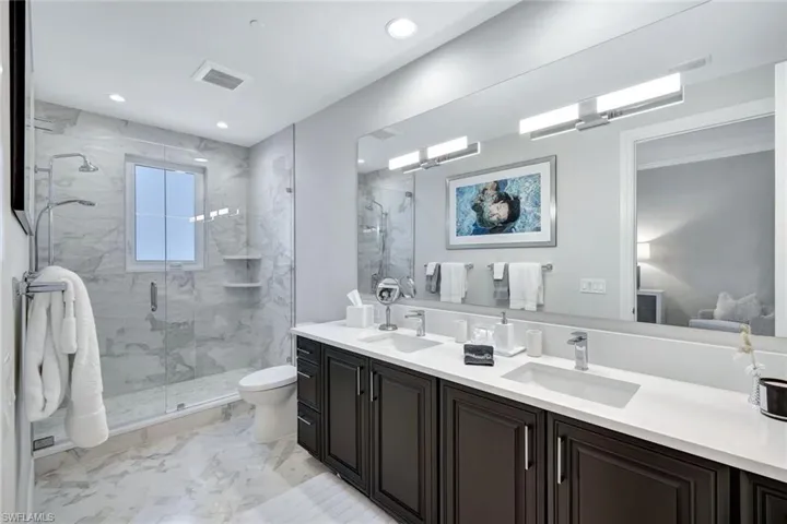 Bathroom with vanity, a shower with shower door, and toilet