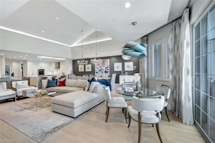 Living room featuring vaulted ceiling, an inviting chandelier, and light hardwood / wood-style flooring