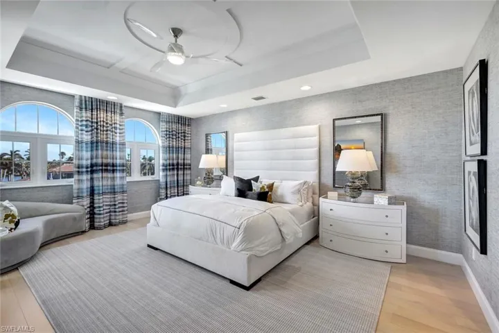 Bedroom featuring ceiling fan, light hardwood / wood-style floors, and a raised ceiling