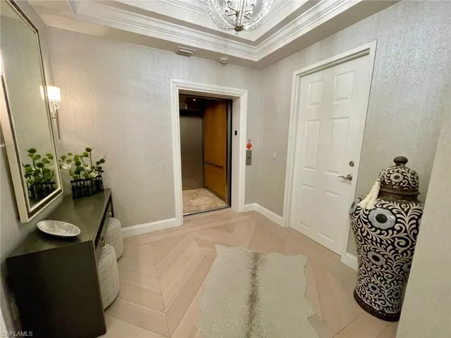 Corridor featuring an elevator, crown molding, and a chandelier