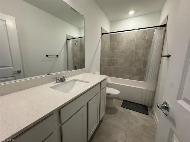 Bathroom featuring vanity, shower / bath combo with shower curtain, and light tile patterned floors