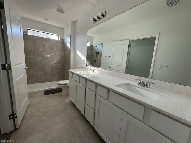 Full bathroom featuring a stall shower, double vanity, and light tile patterned floors