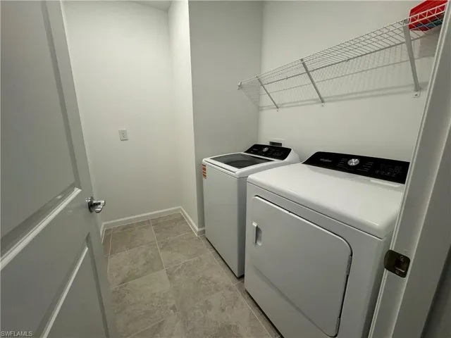 Laundry area featuring washing machine and dryer and baseboards