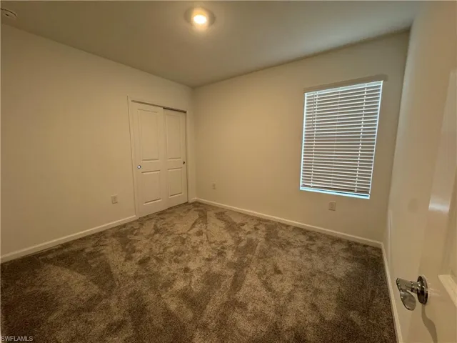 Carpeted spare room featuring baseboards