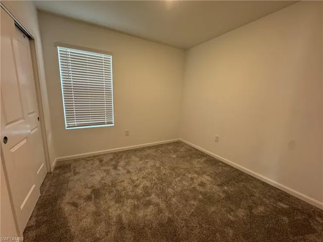 Unfurnished bedroom featuring a closet and dark colored carpet