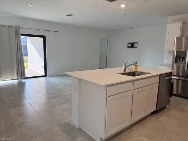 Kitchen with stainless steel appliances, white cabinetry, an island with sink, recessed lighting, and light tile patterned floors