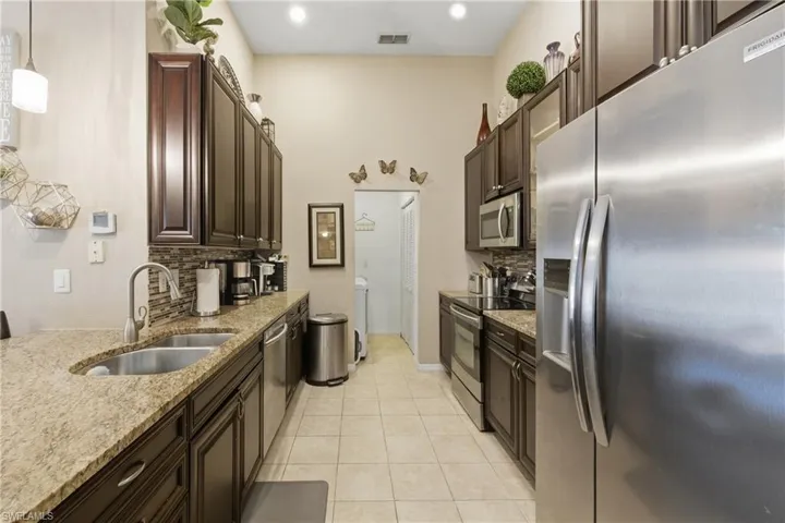 Kitchen featuring stainless steel appliances, tasteful backsplash, and dark wood finish cabinetry