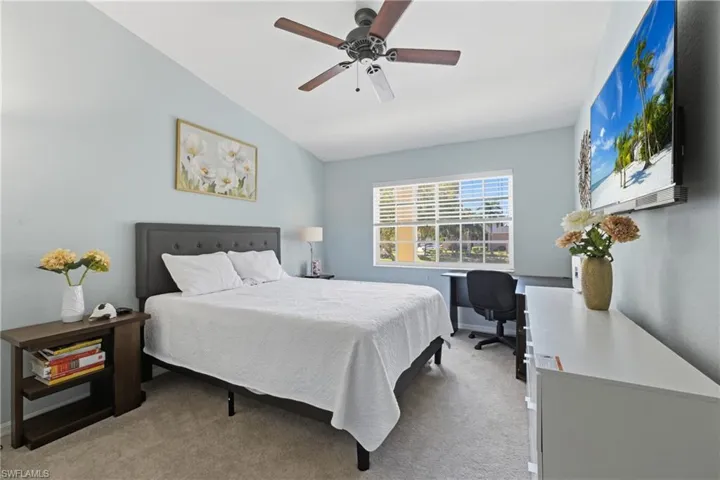 Bedroom with light carpet, an office area, and ceiling fan