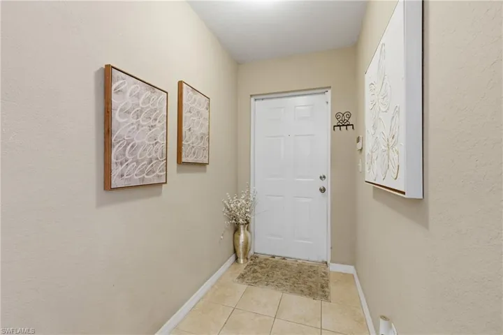 Doorway to outside with a textured wall and tile patterned floors