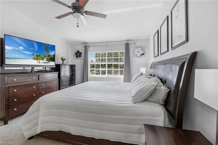 Bedroom featuring vaulted ceiling, light colored carpet, and a ceiling fan