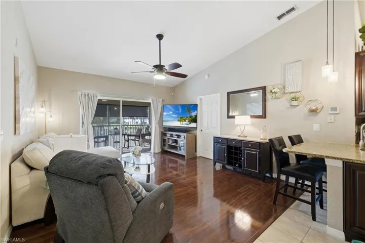 Living room featuring vaulted ceiling, ceiling fan, and dark wood-style flooring
