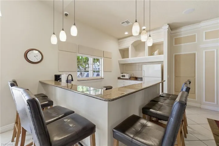 Kitchen featuring a kitchen bar, light tile patterned flooring, a peninsula, and decorative light fixtures
