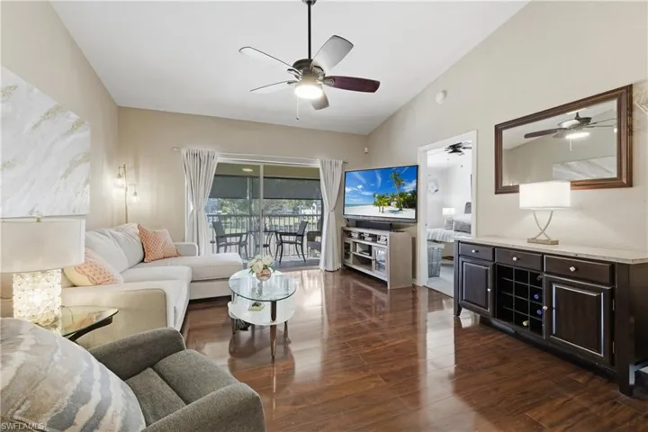 Living area featuring dark wood-style floors, lofted ceiling, and a ceiling fan