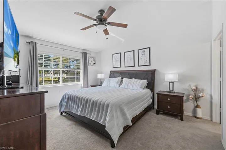 Bedroom featuring light colored carpet, ceiling fan, and lofted ceiling