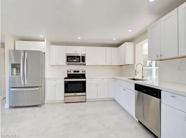 Kitchen with stainless steel appliances, white cabinetry, recessed lighting, and light flooring