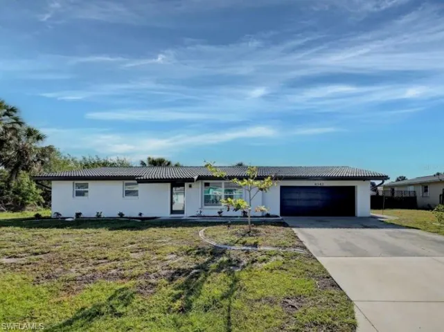 Single story home with a front lawn, driveway, an attached garage, and a tiled roof