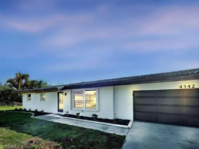 Ranch-style house featuring driveway, stucco siding, and an attached garage
