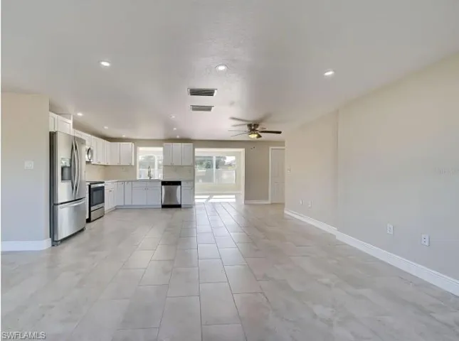 Kitchen with white cabinets, stainless steel appliances, light countertops, recessed lighting, and open floor plan