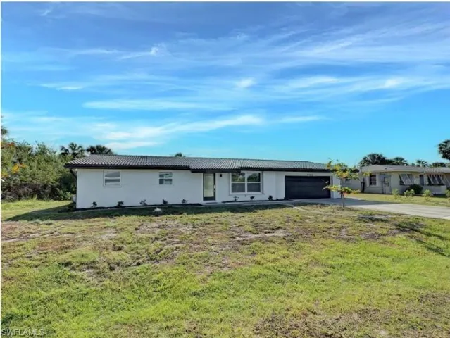 Ranch-style house featuring driveway, a front yard, and a garage
