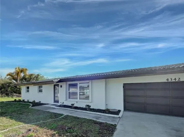 Single story home with stucco siding, driveway, a front yard, a garage, and a tile roof
