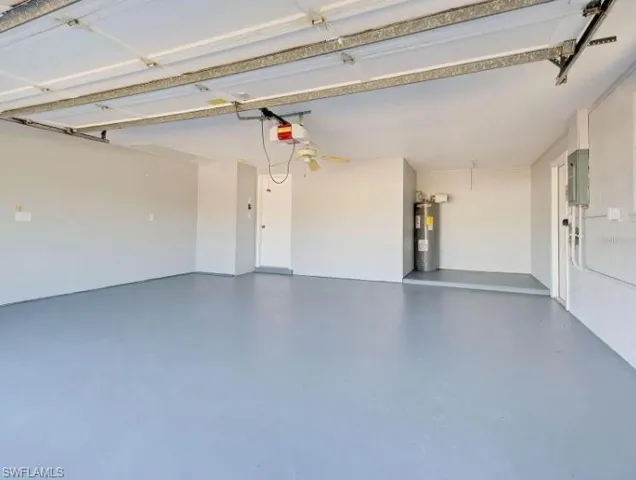 Garage with water heater, electric panel, and a garage door opener