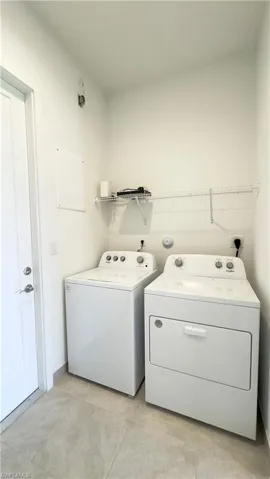 Laundry area featuring washing machine and clothes dryer and light tile patterned floors