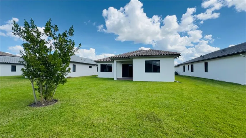 Rear view of house with a patio, a lawn, and stucco siding