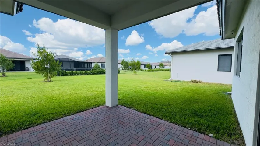 View of green lawn with a patio and a residential view
