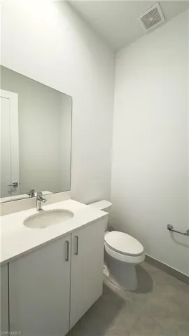 Half bathroom with vanity, a textured ceiling, and dark tile patterned flooring