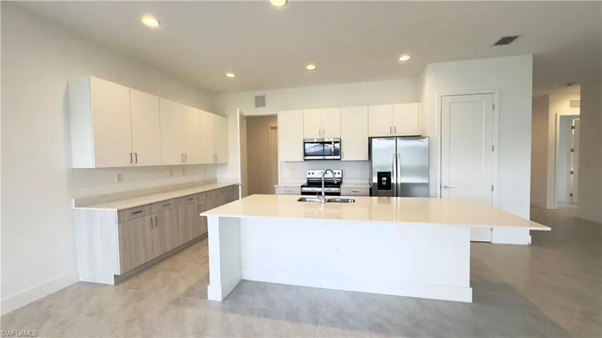 Kitchen with appliances with stainless steel finishes, white cabinets, an island with sink, recessed lighting, and modern cabinets