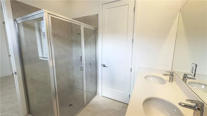 Bathroom with a stall shower, double vanity, and light tile patterned flooring