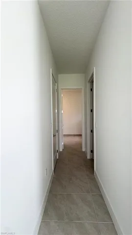 Hall with a textured ceiling and light tile patterned floors