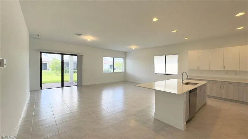 Kitchen with modern cabinets, recessed lighting, a center island with sink, open floor plan, and white cabinets