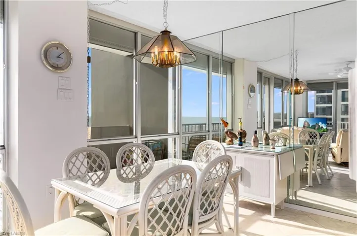 Dining area with tile patterned floors, expansive windows, and hanging lights
