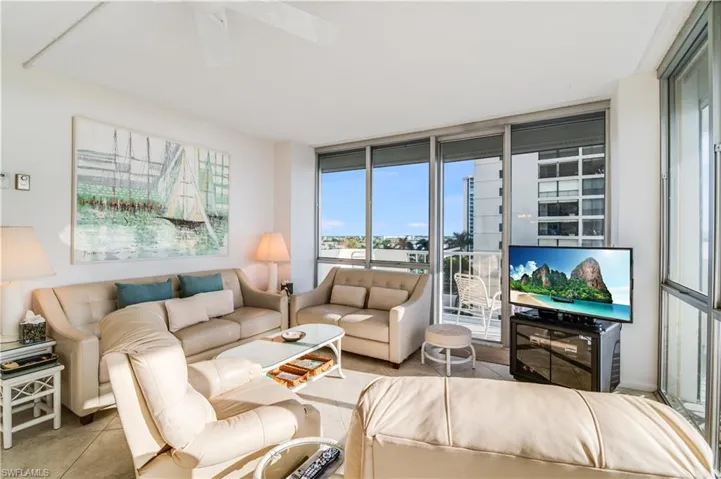 Tiled living area featuring a ceiling fan and floor to ceiling windows