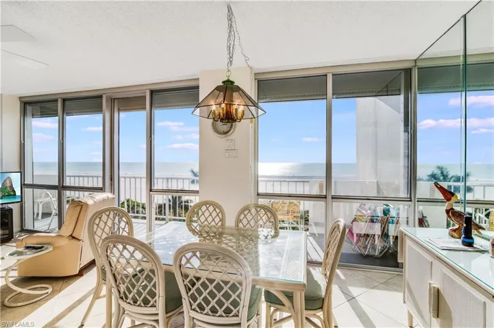 Dining room with floor to ceiling windows, hanging lights, a textured ceiling, a water view, and light tile patterned floors