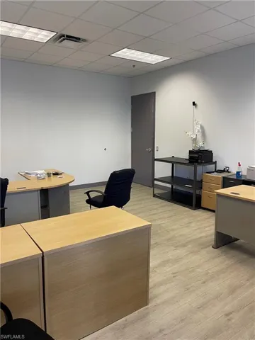 Office area with light wood-type flooring and a drop ceiling
