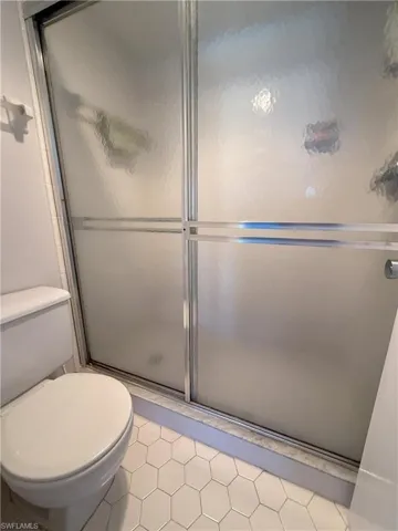 Master Bathroom with tile patterned flooring, toilet, and an enclosed shower