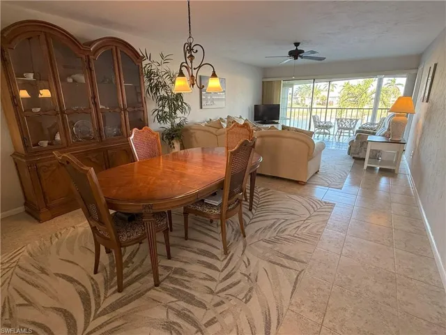 Tiled dining space featuring ceiling fan with notable chandelier